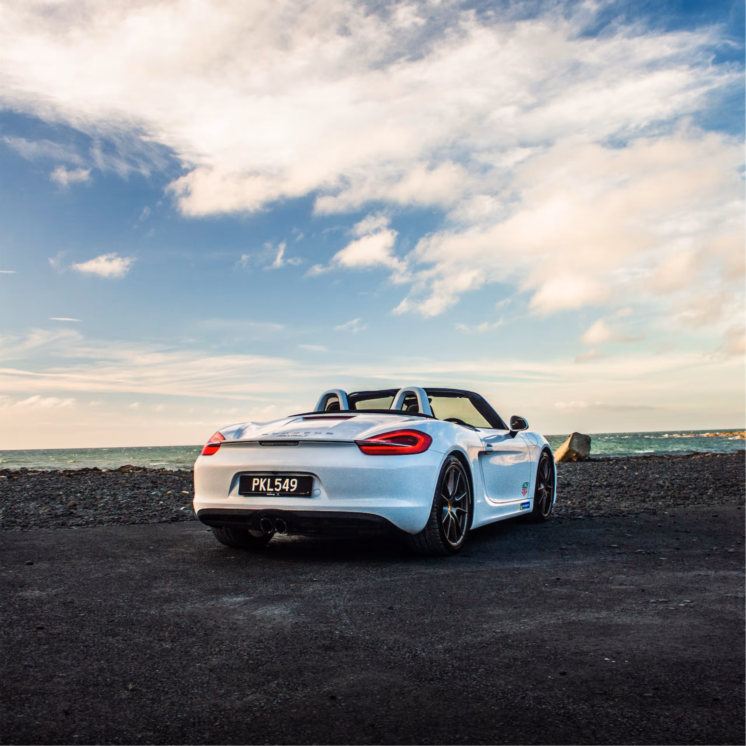 A barista pouring steamed milk into a cup of coffee on a wooden countertop with espresso machines in the background.